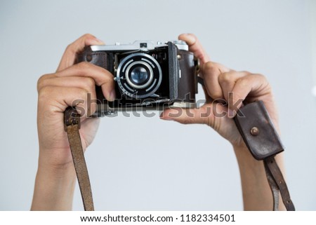 Close-up of female photographer holding old fashioned camera at studio