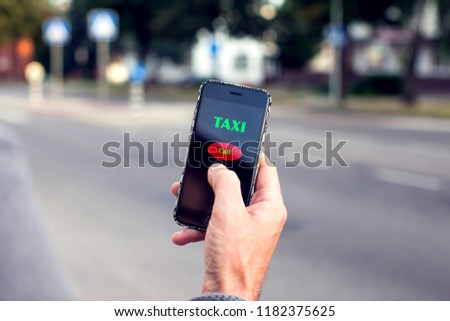 Male hand with smartphone on blurred road background. Taxi service application on the screen.