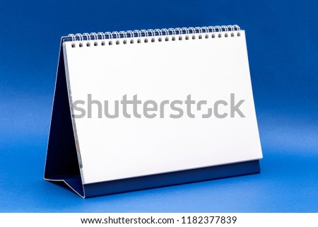 Blank desk calendar on blue background.