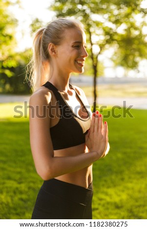 Photo of beautiful young concentrated blonde sports woman in park outdoors meditate.