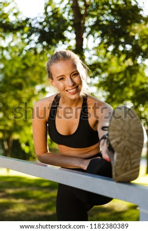 Photo of beautiful young blonde sports woman in park outdoors make stretching sport exercises.