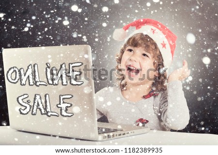 Happy little child with Santa hat and laptop computer,holiday online sale