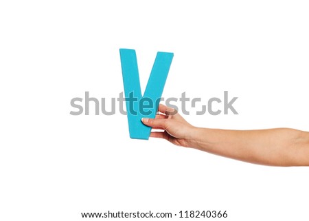 Female hand holding up the uppercase capital letter V isolated against a white background conceptual of the alphabet, writing, literature and typeface