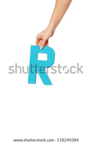 Female hand holding up the uppercase capital letter R isolated against a white background conceptual of the alphabet, writing, literature and typeface