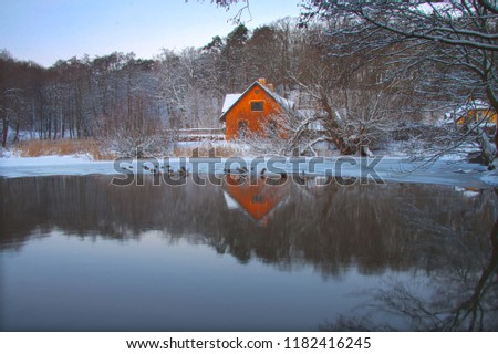 Beautiful lonely house on a lake shore in the forest mirroing the lake in wintertime with snow weather