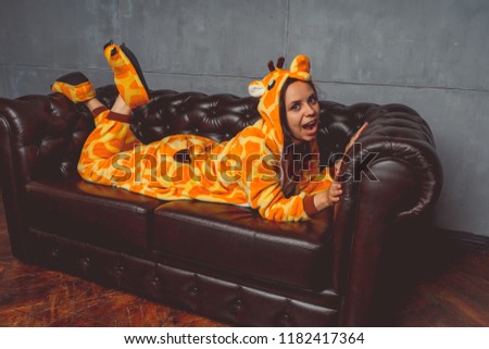 Pajamas in the form of a giraffe. Emotional portrait of a student on the background leather sofa. Crazy and funny man in the suit.