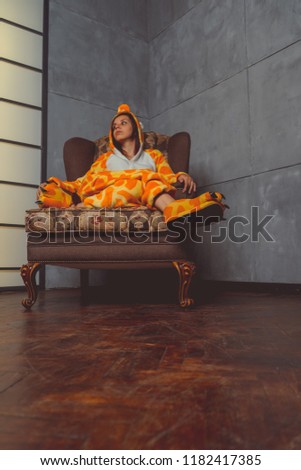 Pajamas in the form of a giraffe. Emotional portrait of a student on the background leather sofa. Crazy and funny man in the suit.
