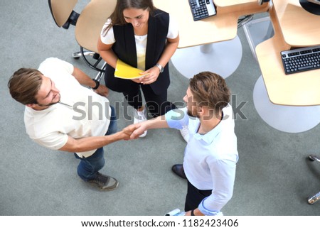 Top view of young business partners shaking hands over deal at office. Focus on hand shake.