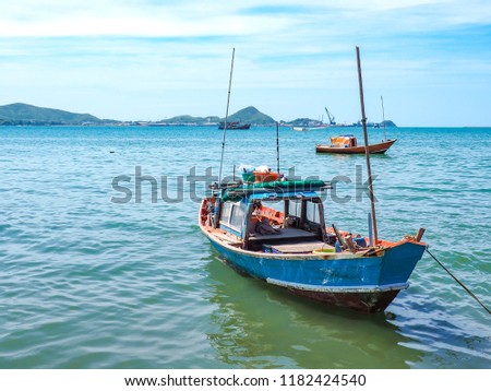 The​ small fishing boats which​ made​ from​ wooden​ are​ anchored in the Gulf of Thailand​ to prepare for fishing in the evening​ and​ blue​ sky​ with​ white​ clouds.