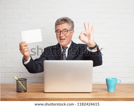 senior businessman working  with his laptop and holding a small card or placard