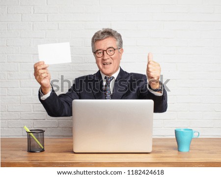 senior businessman working  with his laptop and holding a small card or placard