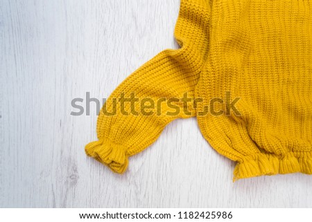 Yellow sweater close-up on a wooden background