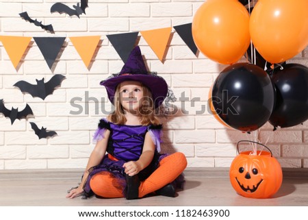 Young girl in halloween costume with balloons and pumpkin bucket