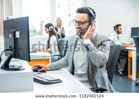 Friendly service agent talking to customer in call centre Royalty-Free Stock Photo #1182482524