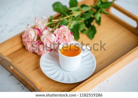 cup of tea with roses on a wooden tray