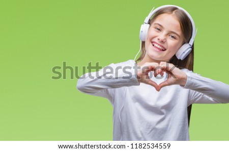 Young beautiful girl wearing headphones listening to music over isolated background smiling in love showing heart symbol and shape with hands. Romantic concept.