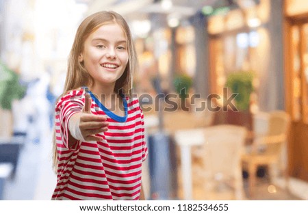 Young beautiful girl over isolated background smiling friendly offering handshake as greeting and welcoming. Successful business.