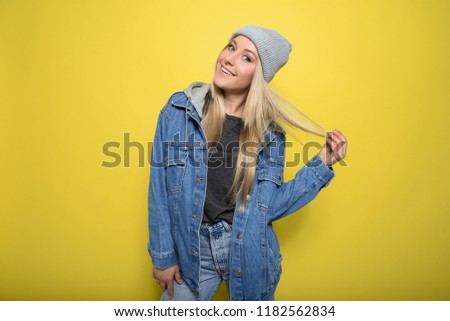 Close up portrait of young attractive woman with blonde straight hair, wearing stylish clothes, have a perfect makeup. Yellow background