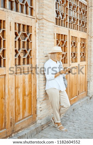 Happy travel woman using smartphone. Portrait of travel tourist girl on vacation texting by mobile phone or walking by map outdoors. Traveler by Central Asia