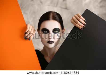 Beautiful woman with Halloween makeup and posters on grey background