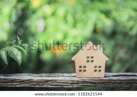 Hard paper house on wood with green background, a symbol for construction , ecology, loan, mortgage, property or home.
