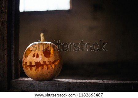 Halloween pumpkin head jack in dark barn on wooden floor. Scary background for poster of celebration of Halloween. Copy space