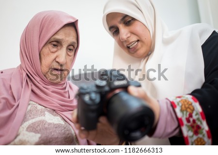 Muslim grandmother with daughter watching pictures on camera
