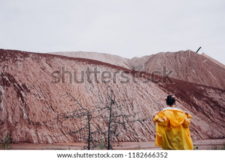 a girl in a bright yellow jacket looks at the red mountains. MARSIAN LANDSCAPES IN BELARUS: SOLIGORSK TERRICONS. 
