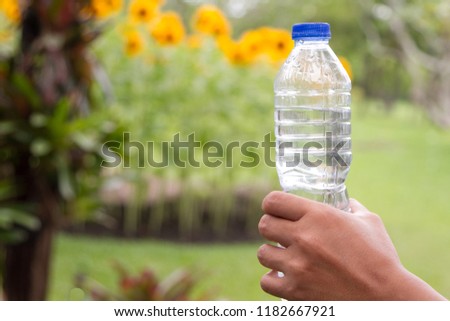 Hand holds a bottle of water in the park Royalty-Free Stock Photo #1182667921