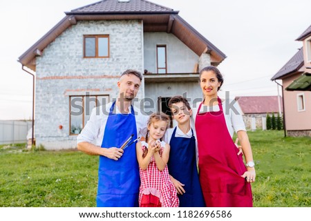 Parents with children son and daughter paitners in aprons hugging while standing together in house on background. The concept of a happy family.