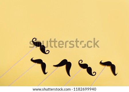 Many black paper Mustache on yellow background. Top view, flat lay. Copyspace for your text. November
