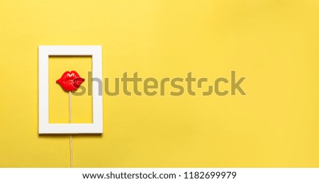 Frame with red lips inside on yellow background. Minimalist concept.