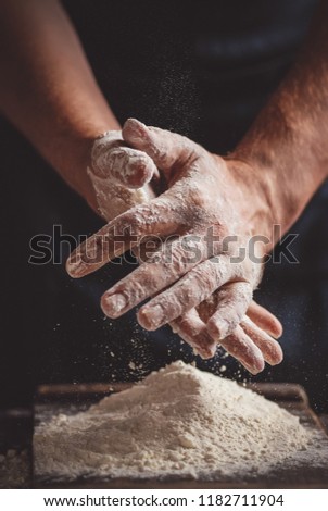 Cooking process: men's hands in flour on a dark background. Close up. Toned picture