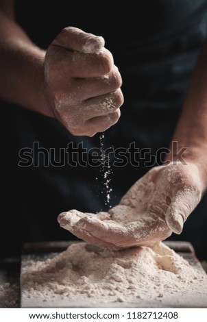 Cooking process: men's hands in flour on a dark background. Close up. Toned picture