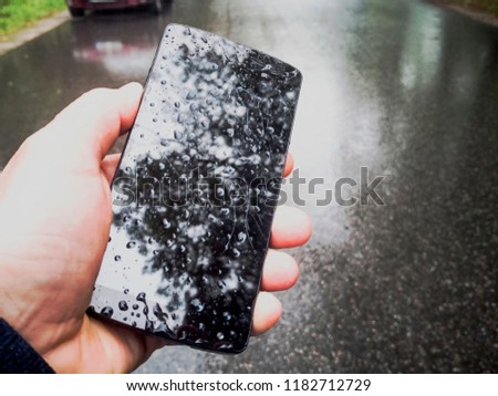 Hand Holding broken and black screen cracked smartphone. Out of order  with highly broken screen on asphalt  background. Used Mobile phone needs repair. Phone dropped down on the ground. Copy space. 