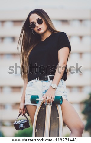 Beautiful young woman posing with retro camera and skate
