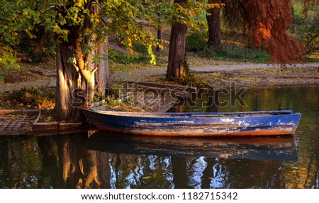 Landscape of a blue boat on the lake in the Carol park on an evening autumn at Bucharest.