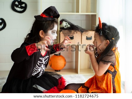 Portrait of two sisters in Halloween costume acting like a ghost frigthening expression to each other in Halloween festival