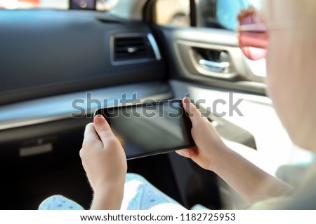  Little girl/ child sitting in a car with a smartphone in a hands