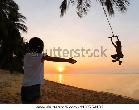 silhouette boy and girl playing swing when sunset time on the beach. Concept of friendly