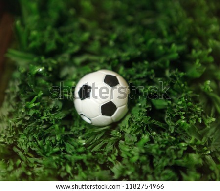 Artificial football field cover. Green grass close-up. Vintage retro grass. Soccer ball lies on the grass