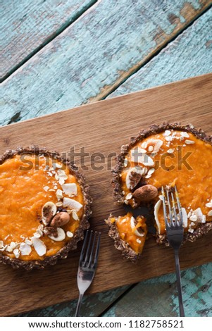Healthy vegetarian dessert. Pumpkin open pies with nuts and oatmeal on wooden board on blue background copyspace