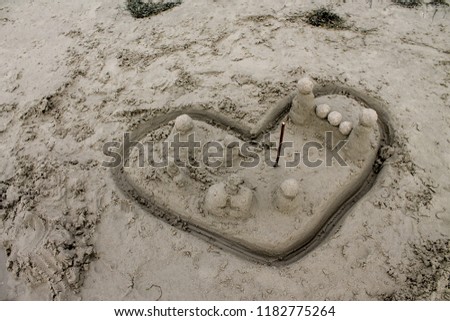 The heart image on the beach sand penetrated by a stick, love theme