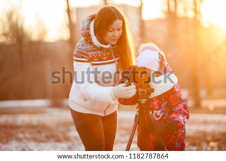 Education photography using tripod and SLR camera. Mom the photographer with child in sunset park