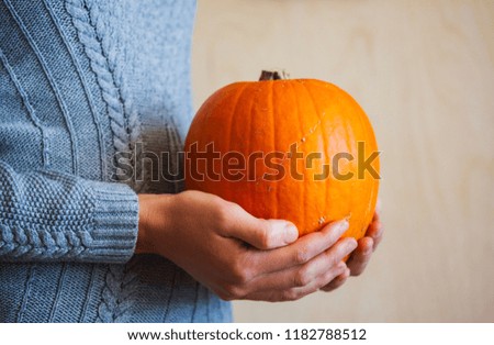 Young Woman in Knitted Sweater Holding Halloween Pumpkin. Cozy Autumn Concept.