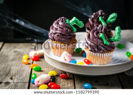 Halloween style sweets - cupcakes with green bones, rustic background