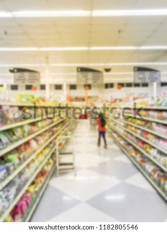 Motion blurred customer shopping for flour, seasonings, dried vegetable, canned sea food shelves at Asian grocery store in USA. Defocused row, aisles of traditional Vietnamese and Chinese dressing