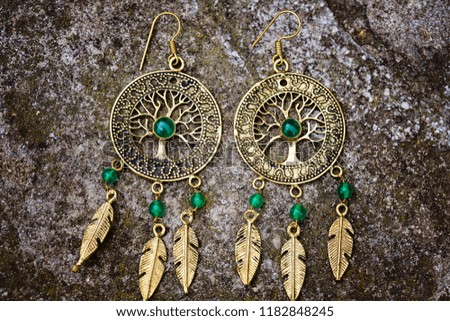Indian spiritual ornamental style brass earrings on rocky background