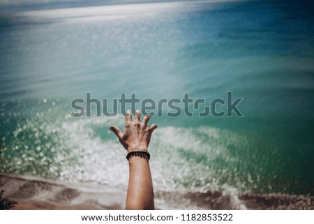 male hand over the sea. vacation at sea. Top view of the azure sea and summer beach