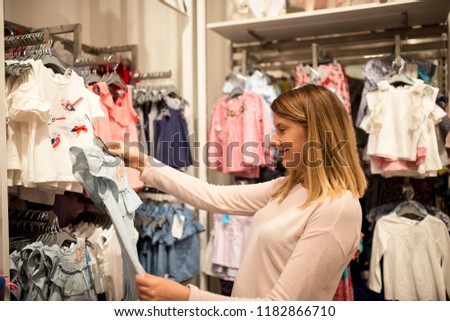 Young woman choosing clothes on a rack in a showroom, Beautiful woman buying clothes